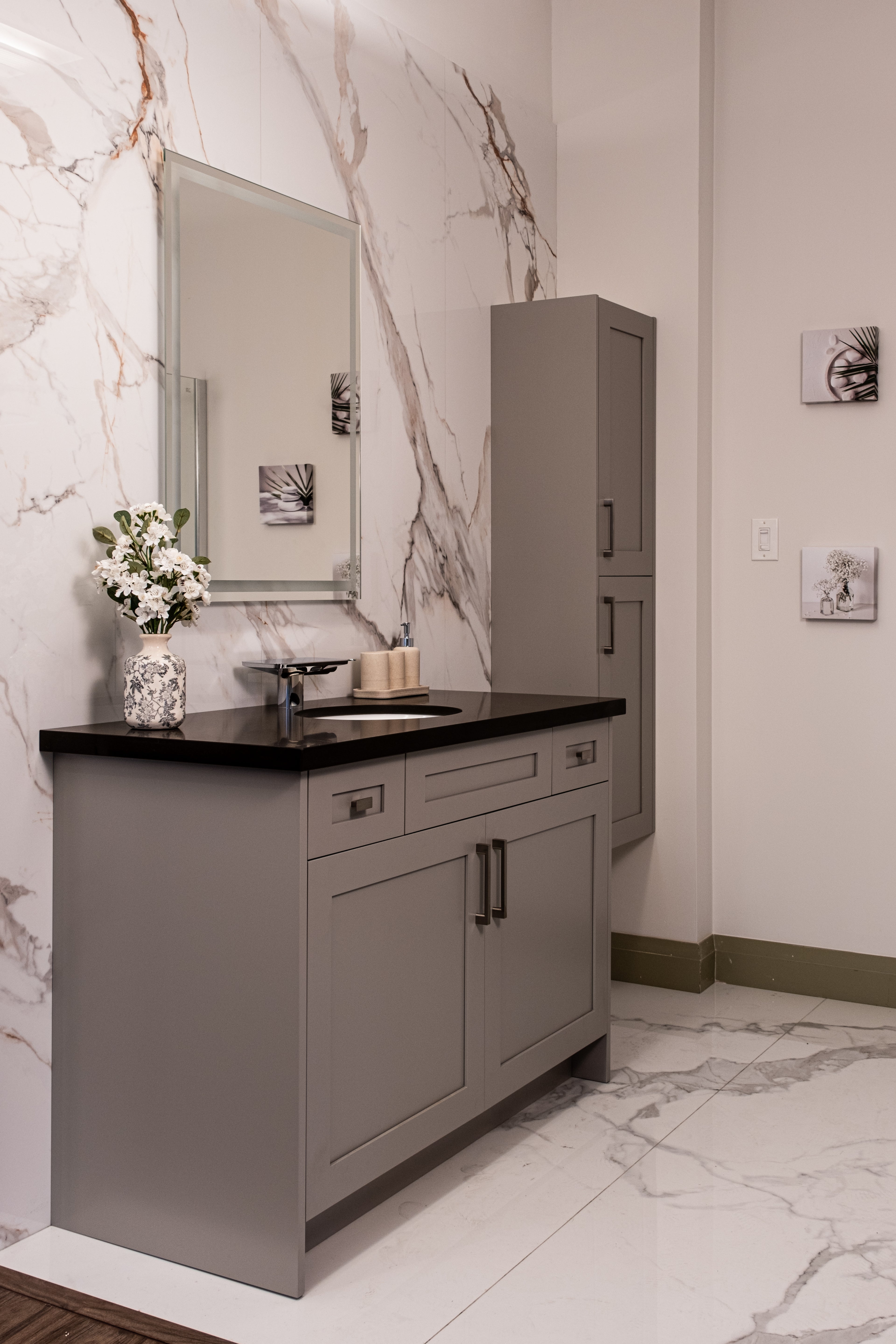 Stylish modern bathroom with gray cabinetry, black solid-surface countertop, and polished marble walls by RTA & RTI Cabinets.